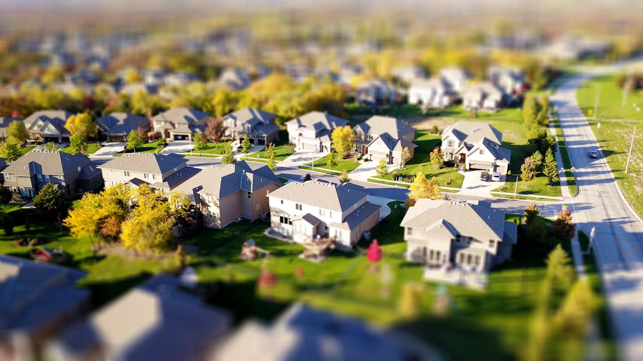 journey Tilt-shift aerial photo of a suburban neighborhood with green lawns and roads.